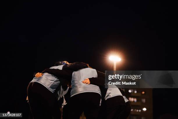 female soccer team in huddle against sky at night - briefing stockfoto's en -beelden