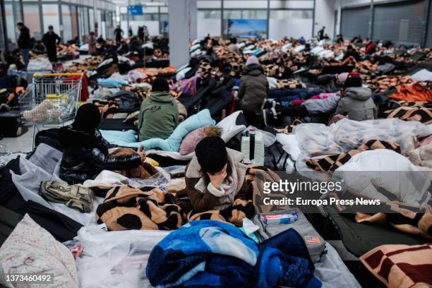 Several people rest in a shopping center intended as the temporary reception of refugees coming to Poland in search of refuge, February 28 in Mylny,...