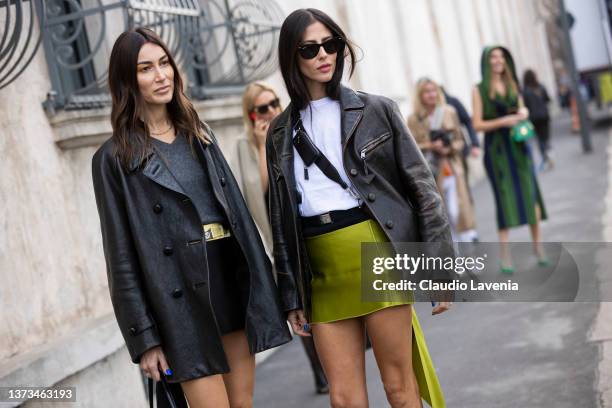 Giorgia Tordini and Gilda Ambrosio pose ahead of the Prada fashion show wearing a grey sweater, black mini skirt, black leather jacket, Prada black...