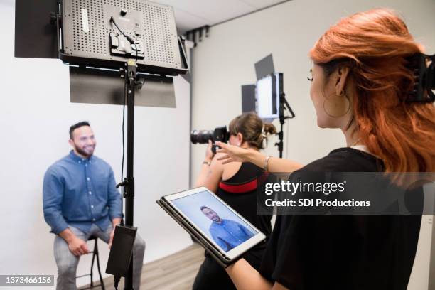 fotograf schießt männerfotos, während der assistent anweisungen gibt - fotosession stock-fotos und bilder