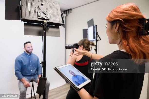 le photographe prend des photos d’homme pendant que l’assistant donne des instructions - séance photo photos et images de collection