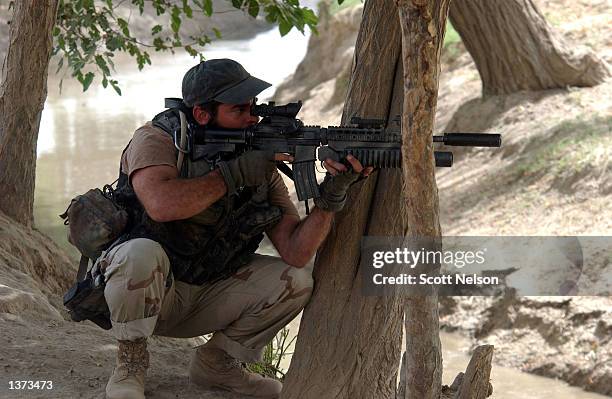Army Special Forces soldier nicknamed "Porno" watches a suspicious person through his rifle scope during an operation August 24, 2002 in the village...
