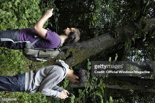 Two men checking their position on cell phones with GPS in a forest while geocaching on July 5 Monkton Farleigh.