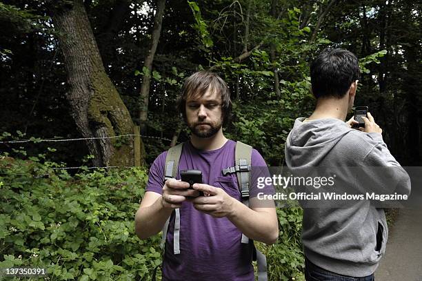 Two men checking their position on cell phones with GPS in a forest while geocaching on July 5 Monkton Farleigh.