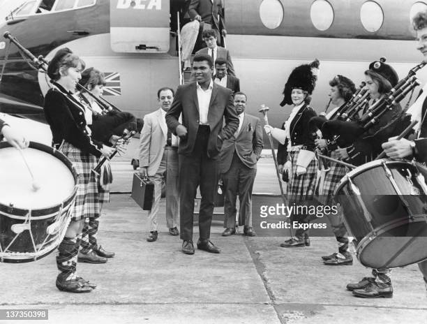 American WBC world heavyweight boxing champion Muhammad Ali is greeted by a traditional Scottish pipe band on his arrival at Glasgow Airport, 18th...