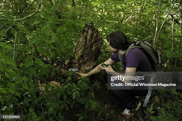 Man discovering a geocache in a lush forest while geocaching on July 5 Monkton Farleigh.