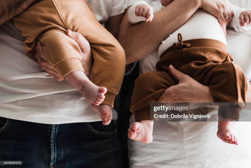 Primer plano de las piernas y los pies del bebé en las manos de los padres