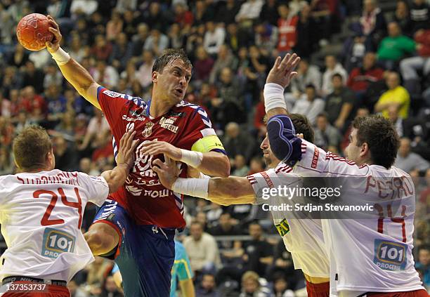 Momir Ilic of Serbia, throws the ball over Martin Stranovsky and Andrej Petro of Slovakia, during the Men's European Handball Championship 2012 group...