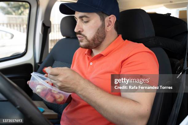 delivery man with uniform eating while sitting inside the van - eating in car stock pictures, royalty-free photos & images