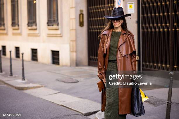 Katya Tolstova poses ahead of the Giorgio Armani fashion show wearing olive green sweater maxi dress, brown leather belt, brown leather trench coat,...