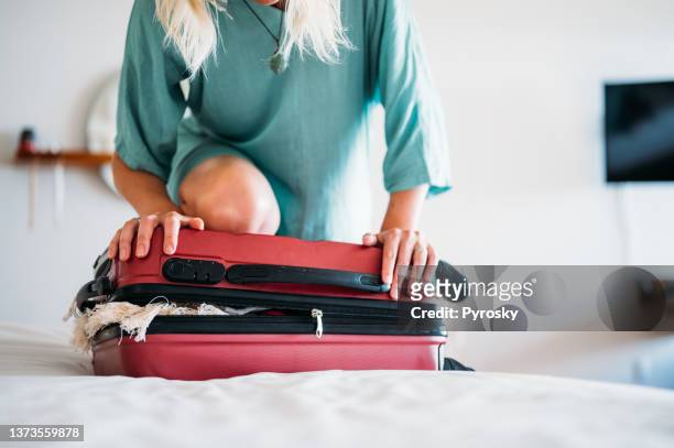 une femme a un problème avec la fermeture de la valise - hand on knee stock photos et images de collection
