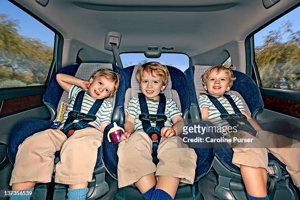 boy triplets in the back of a car - kid car seat stock-fotos und bilder