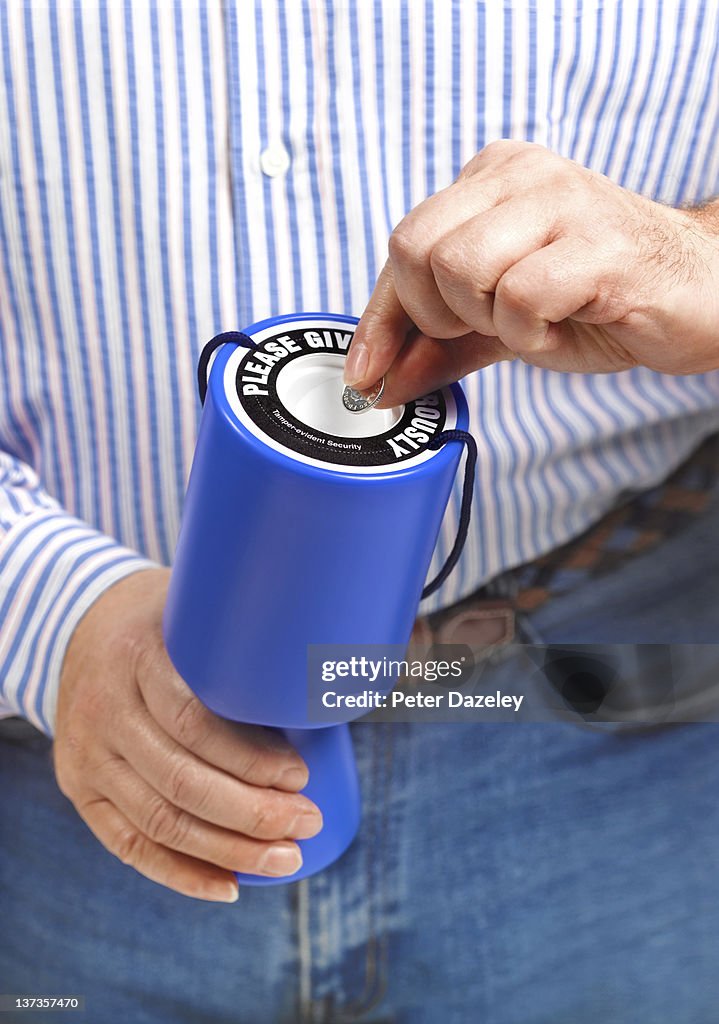 Putting coin into charity donation box