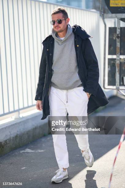 Guest wears black sunglasses, a white t-shirt, a pale gray hoodie sweater, a black hoodie coat, white denim jeans pants, white fabric and gray suede...