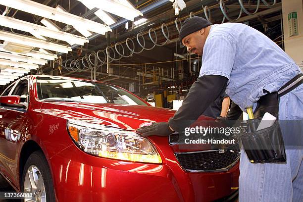 In this handout provided by General Motors, employee Maurice Vauss inspects the fit and finish of the 2013 Chevrolet Malibu Eco during final...