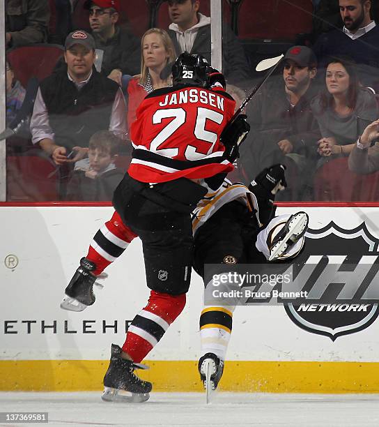 Cam Janssen of the New Jersey Devils hits Andrew Ference of the Boston Bruins at the Prudential Center on January 19, 2012 in Newark, New Jersey.