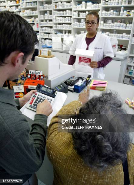 Canadian pharmacist technician Florence Ticne waits for Mona Thompson of Minnesota to view her savings as senior federation organizer Max Neuhaus...