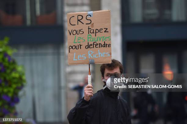 Man holds a placard that reads, ' CRS you bash the poor to defend the rich', during a protest in Nantes, western France on June 30 after the shooting...