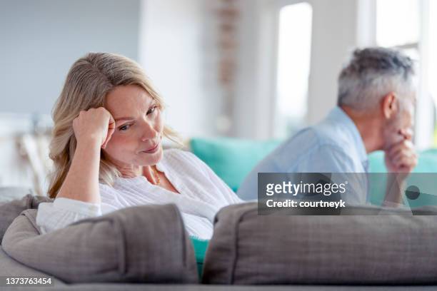 mature couple fighting at home sitting on the sofa. - mêl�ée stockfoto's en -beelden