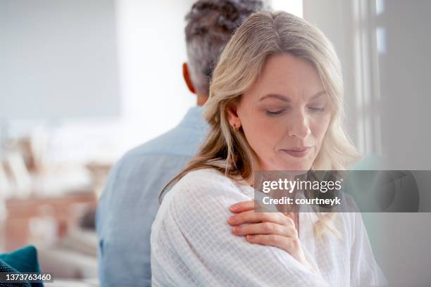 pareja madura peleando en casa sentada en el sofá. - sadness fotografías e imágenes de stock