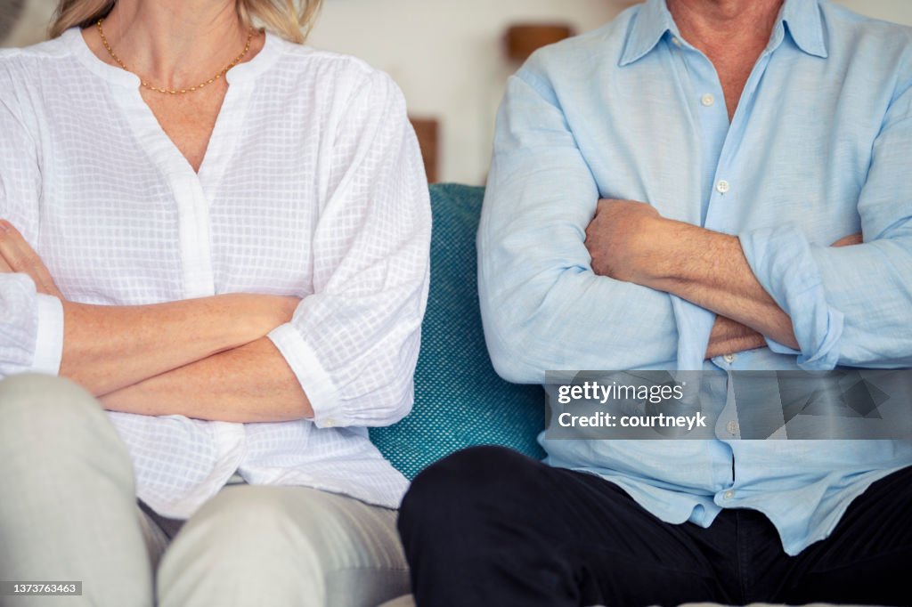 Mature couple fighting at home sitting on the sofa.