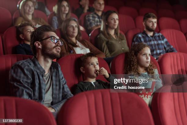 single father with kids in cinema - movie stock pictures, royalty-free photos & images