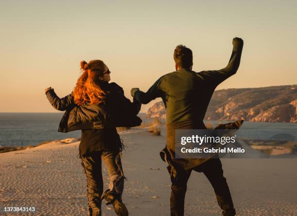 rear view of couple jumping at duna da cresmina - vista posterior stock pictures, royalty-free photos & images