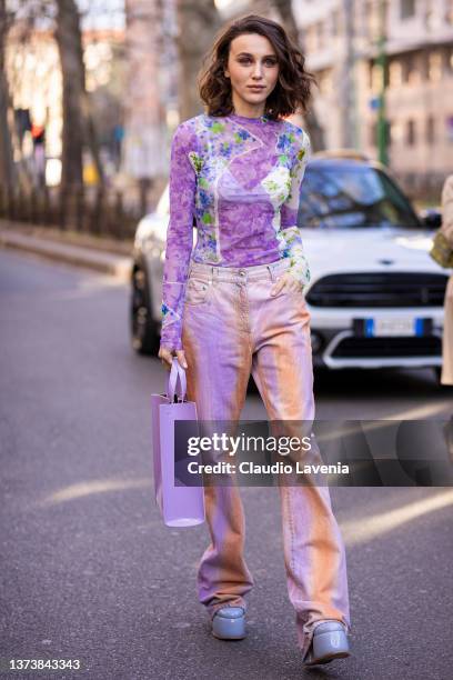 Mary Leest poses ahead of the MSGM fashion show wearing a pink printed sheer top, orange and pink tie dye jeans, lilac bag and lilac platform heels...