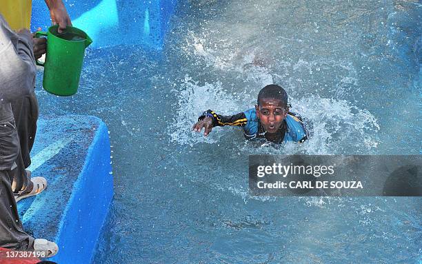 An Ethiopian Orthodox Christian boy falls into cross shaped pool of water blessed by priests during the annual festival of Timkat in Lalibela,...