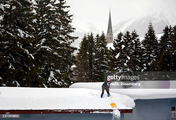 Man uses a shovel to clear snow from a rooftop in the town of Davos, the venue of the World Economic Forum's 2012 annual meeting, in Davos,...