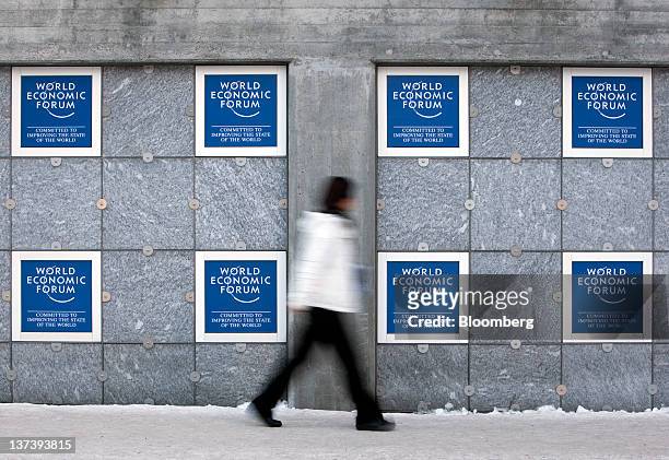 Pedestrian walks past posters outside the Congress Centre, the venue of the World Economic Forum's 2012 annual meeting, in the town of Davos,...