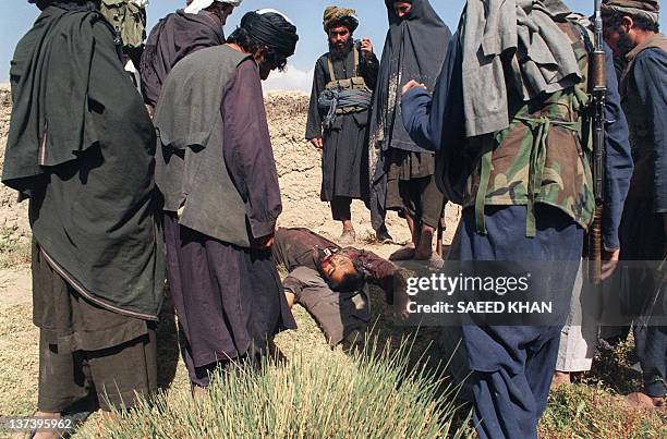 Soldiers belonging to religious Taliban militia gather around a dead body of a local villager accused of collaborating with former government forces...