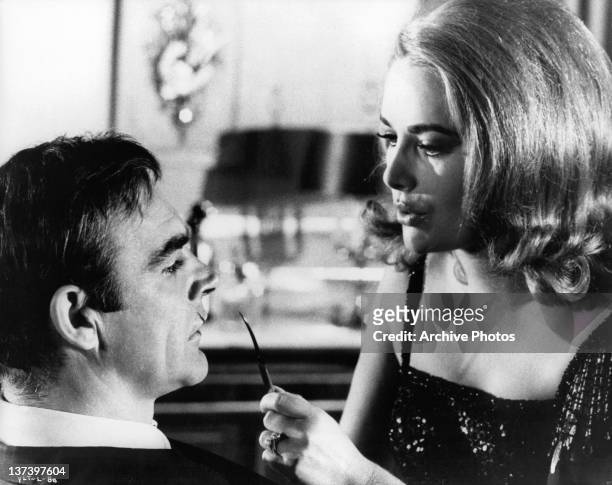 Actress Karin Dor has a sharp utensil up to Sean Connery's face in a scene from the film 'You Only Live Twice', 1967.
