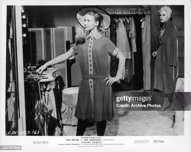 Kim Novak watching an unknown actress try on a hat while looking in the mirror in a scene from the film 'Jeanne Eagels', 1957.