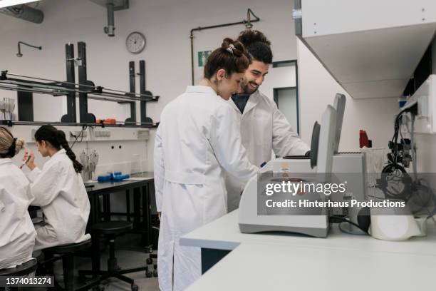 medical students using lab equipment together - biochemical foto e immagini stock