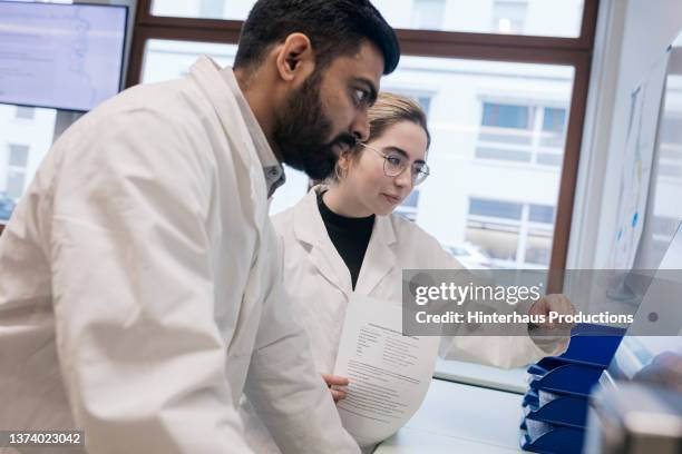 two medical students looking at computer screen in lab - medical research paper stock pictures, royalty-free photos & images