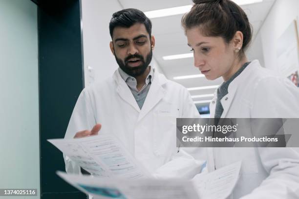 two medical students looking over paperwork - medical research paper stock pictures, royalty-free photos & images