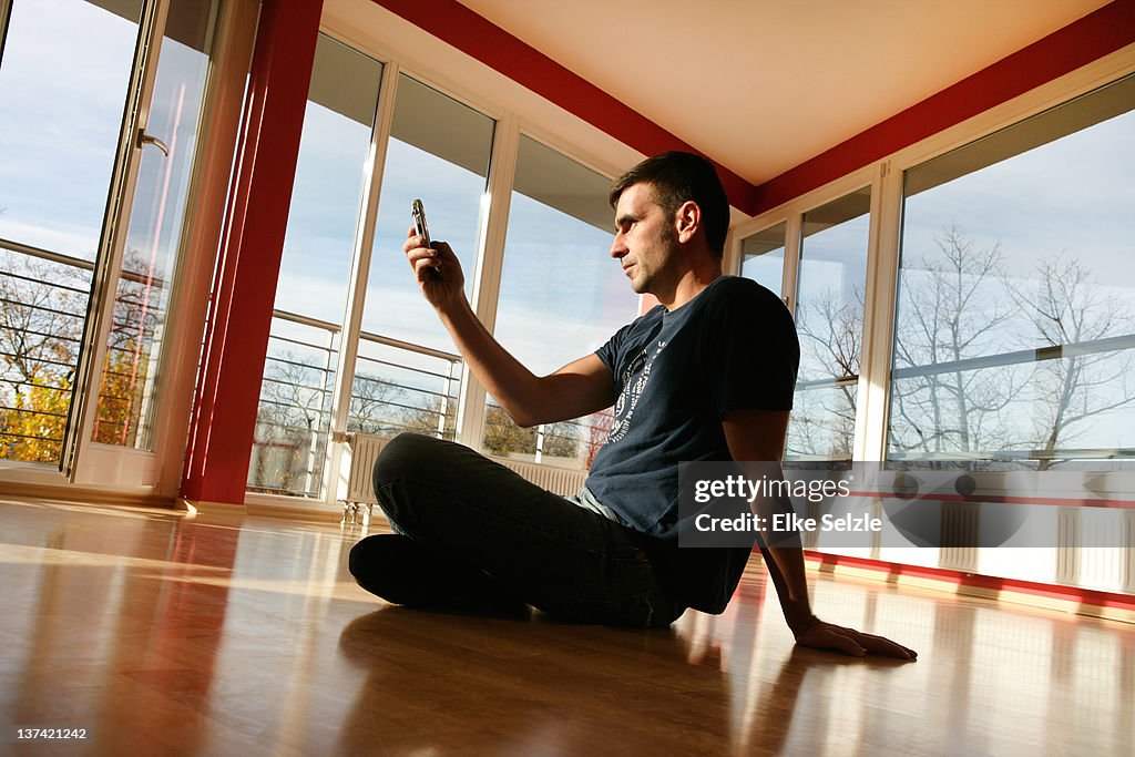 Man sitting in new apartment checking mobile phone