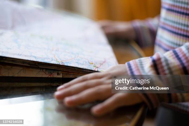 young mixed-girl enjoys learning to read a paper map as family prepares for road trip - solo bambini foto e immagini stock
