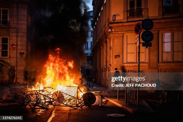 Smoke rises from a bonfire near a graffiti reading "The police kills" during clashes with police in the streets of Lyon, south-eastern France, on...