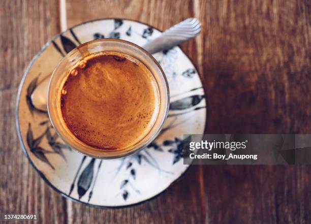 high angle view of a cup of dirty latte served on a plate on wooden table. - crema stock pictures, royalty-free photos & images