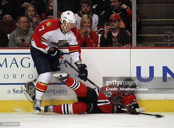Marcus Kruger of the Chicago Blackhawks manages to knock the puck away from Dmitry Kulikov of the Florida Panthers after falling down at the United...