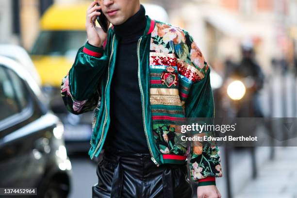 Guest wears a black turtleneck pullover, a dark gray with beige / brown / pink flower print pattern gold shiny strap and red embroidered sequined...