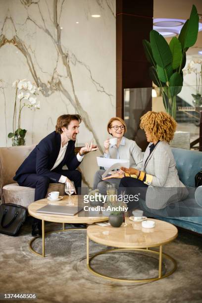 business partners sitting down at the hotel lobby looking and reviewing documents. - businesswoman hotel stock pictures, royalty-free photos & images