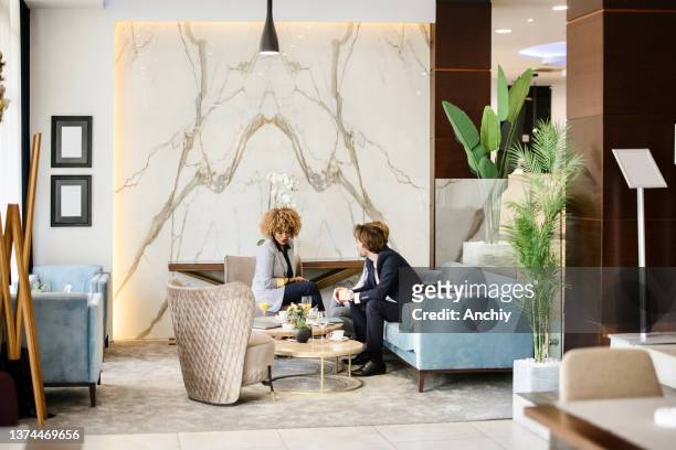 business partners sitting down at the hotel lobby looking and reviewing documents. - business meeting coffee stock pictures, royalty-free photos & images