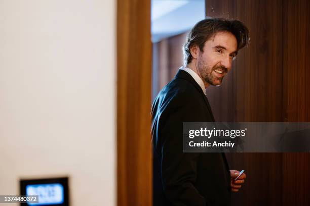 geschäftsmann mit zimmerschlüsselkarte, um die tür zu entriegeln und das hotelzimmer zu betreten - hotelzimmer tür stock-fotos und bilder