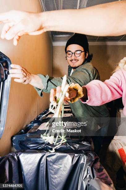 young woman putting leftovers while friends opening garbage bin at college dorm - mixed recycling bin stock pictures, royalty-free photos & images