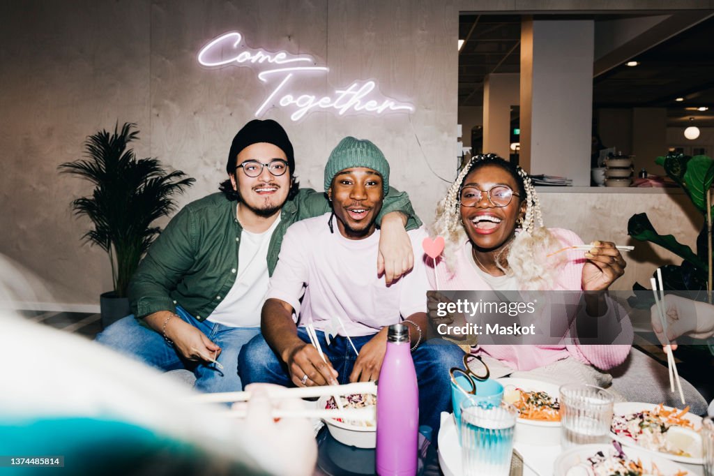 Portrait of cheerful multiracial male and female friends enjoying meal in college dorm