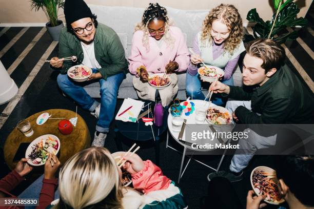 high angle view of multiracial male and female students enjoying food in college dorm - college dorm party stock-fotos und bilder
