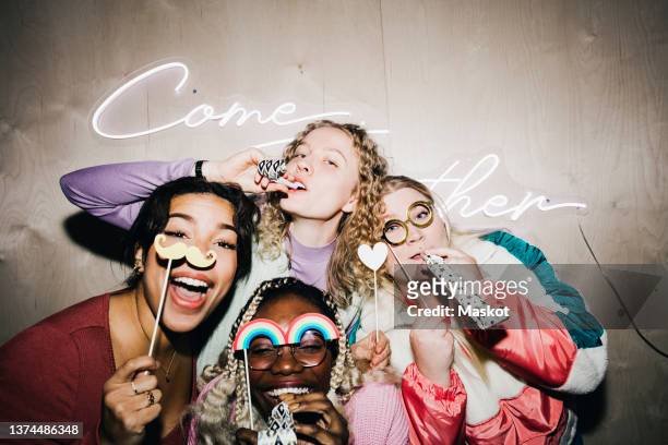 portrait of carefree multiracial female friends with props enjoying in college dorm - campus party stockfoto's en -beelden